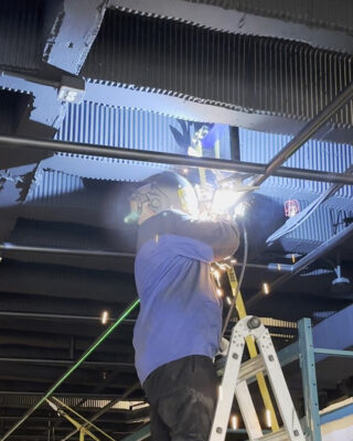 Installation par un soudeur de VF métal du grillage en métal ouvré au plafond du théâtre du Collège Lionel-Groulx